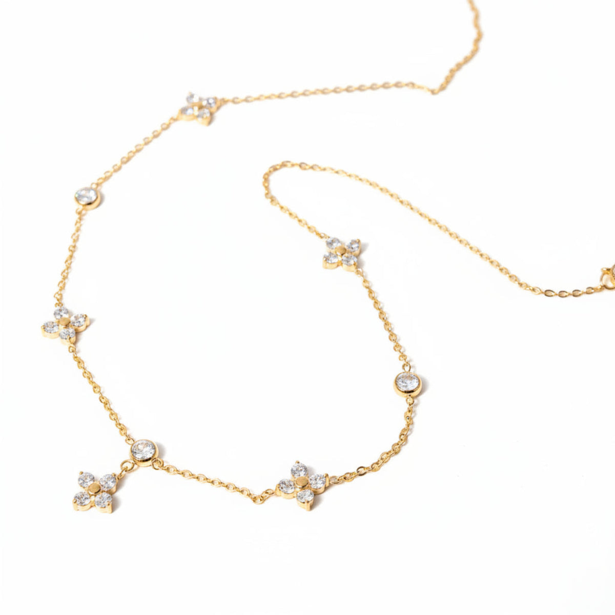 Gold necklace with diamond-like stones on a beige stone surface
