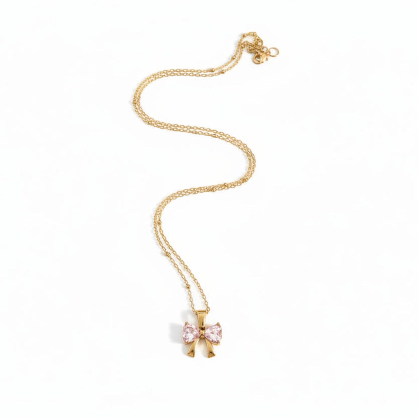 A delicate gold chain necklace featuring a bow-shaped pendant with light pink gemstones, displayed on a clean white background.