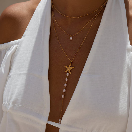 Starfish necklace with pearls on a person wearing a yellow top